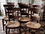 six chaises en bois disposées dans une pièce au sol carrelé
