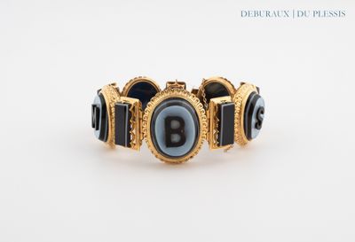 un bracelet noir et doré orné d'une lettre « b »