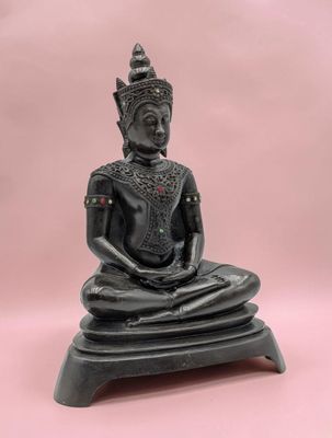 une statue de Bouddha noire posée sur un socle en bois