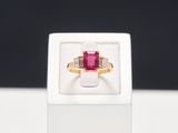 a close up of a ring in a white box with a red stone