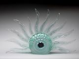 une sculpture en verre représentant une urne marine posée sur une surface blanche