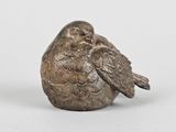 une vieille figurine en argent représentant un oiseau perché sur un rocher