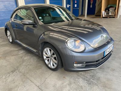 La Coccinelle Volkswagen est garée dans un garage, devant une porte de garage bleue.