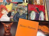many books on a table with a vase on top of it