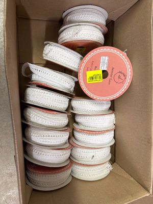 une boîte en carton remplie d'une multitude de bobines blanches et roses