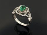 une bague en émeraude et diamant sur une surface noire