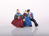 three figurines of people sitting on a white surface