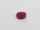 a pink ruby stone on a white surface