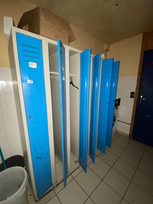 Plusieurs casiers bleus sont alignés les uns à côté des autres dans des toilettes publiques