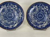 two blue and white plates with designs on them sitting on a table