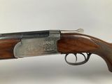 a shotgun with a wooden handle and a silver plated handle