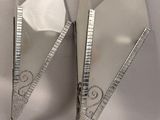 pair of silver plated triangular shaped mirrors on a white surface