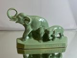 a green elephant with two baby elephants on top of it