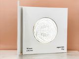 a white box with a silver coin on top of it