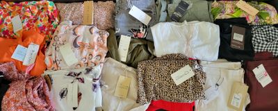 une valise pleine de vêtements, dont certains ont encore leurs étiquettes