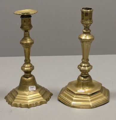 une paire de bougeoirs anciens en laiton posés sur une table blanche