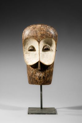 une image représentant un masque en bois posé sur un socle métallique