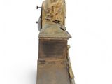 statue of a woman sitting on top of a wooden bench