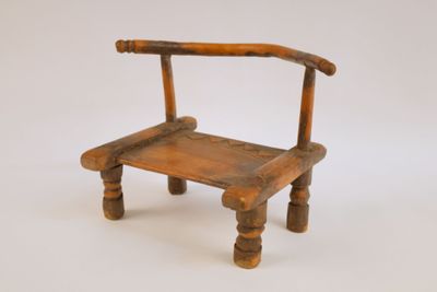 une petite chaise en bois posée sur une surface blanche
