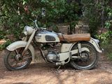 une moto garée sur la terre battue près de quelques arbres
