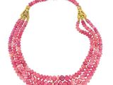 un collier à trois rangs de perles roses rehaussé de touches dorées