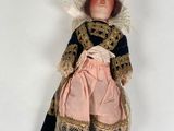 an antique doll of a woman in a pink dress and hat