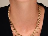 a woman wearing a gold chain necklace and black top