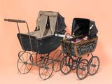 an old fashioned baby carriage with a baby in it on a pink background