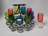 de nombreux verres de différentes couleurs et un verre à vin sur la table
