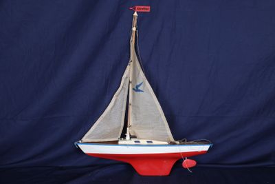 maquette d'un voilier posée sur un socle, sur fond bleu