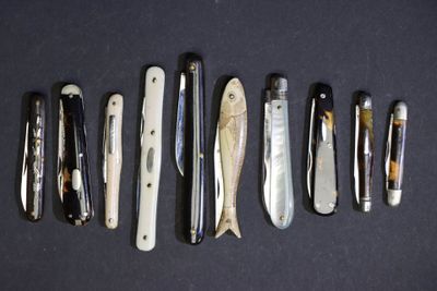 plusieurs types de couteaux sont alignés sur une surface noire