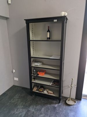 une bibliothèque noire sur laquelle est posée une bouteille de vin