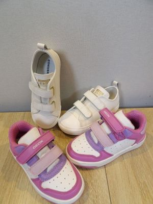 two pairs of white and pink shoes on a wooden floor