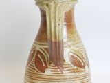 a brown and white vase sitting on a white surface
