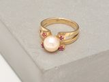 bague en or ornée d'une perle et de rubis posés sur un bloc