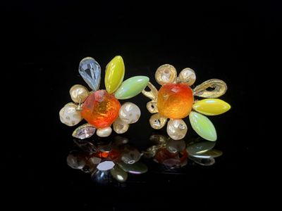 une paire de boucles d'oreilles en forme de fleurs en verre jaune et orange sur un fond noir