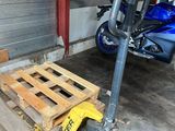 a blue motorcycle parked in a garage next to a wooden pallet