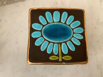 a small blue flower on a black and brown plate