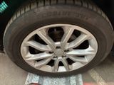someone standing next to a car with a flat tire on the ground