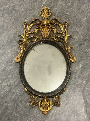 un gros plan d'un miroir posé sur une table, avec un cadre noir et doré