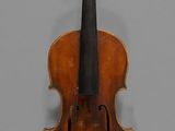 an old violin sitting on top of a table next to a gray wall