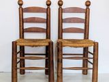 two wooden chairs sitting next to each other on a white floor