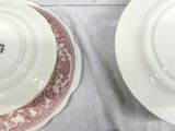 two white plates with red designs on them sitting on a table