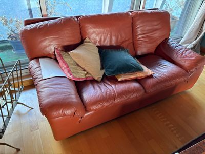 a red leather couch with pillows on it in a living room