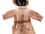 un mannequin vêtu d'un manteau et d'un chapeau, posé sur un socle
