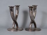 two silver candlesticks sitting on top of each other