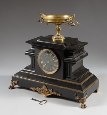 an antique black and gold clock with a bowl on top of it