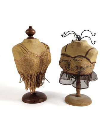 pair of mannequins with fringes on stands against a white background