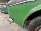 a green truck parked in a lot with other cars