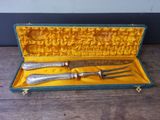 two forks and a knife in a case on a table
